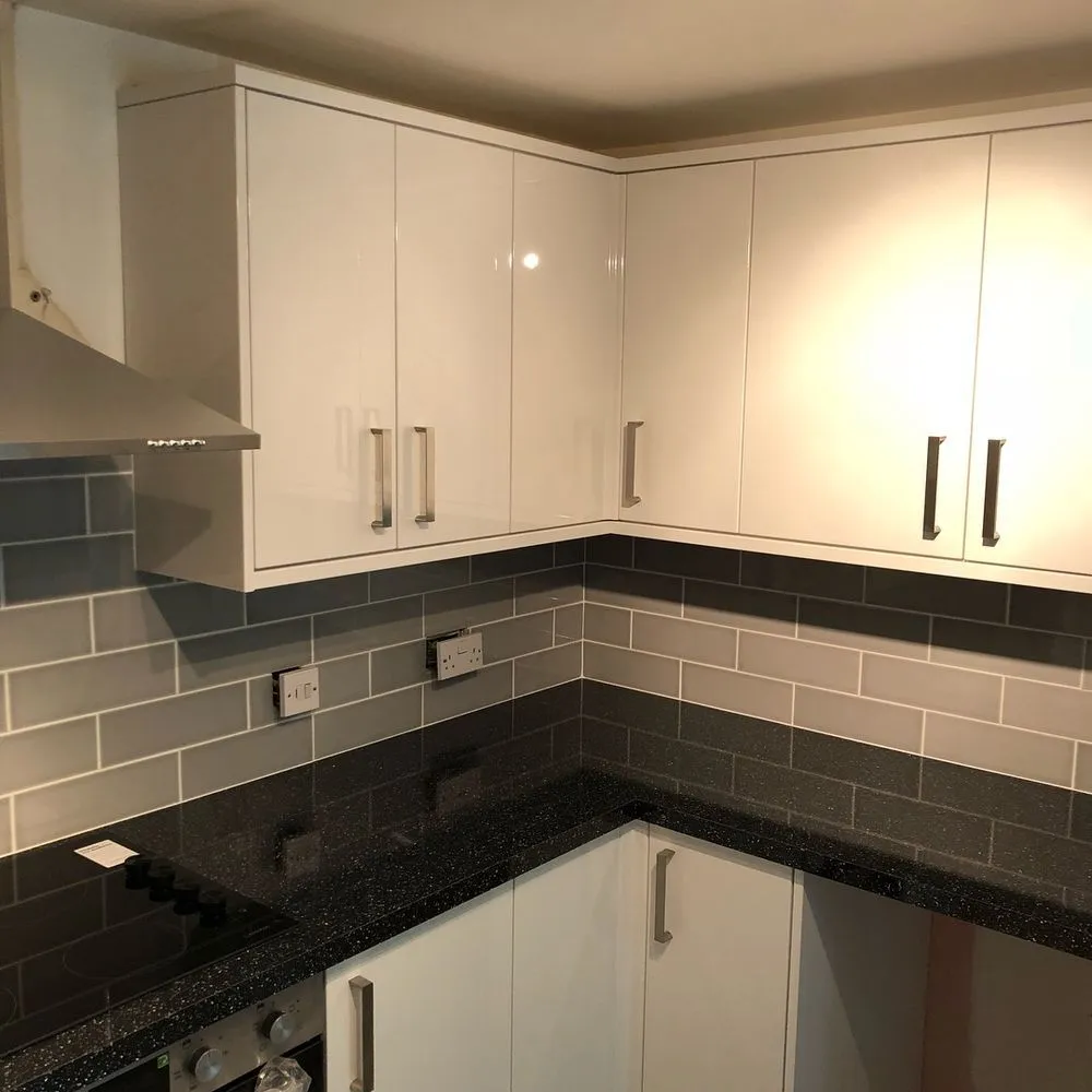 Gloss white contemporary kitchen with black granite worktop and grey subway tile splashback, finished in Bedminster