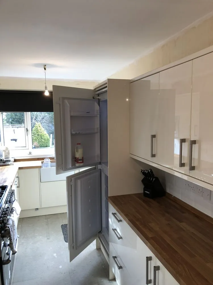 Cream gloss contemporary kitchen with oak worktop, range cooker, and Belfast sink, photographed mid-completion in Redland