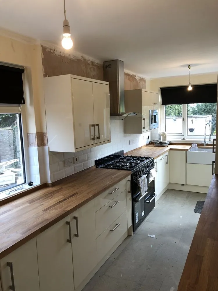 Cream contemporary kitchen with oak worktop, black range cooker, Belfast sink, and white subway tiles, photographed mid-completion in Redland