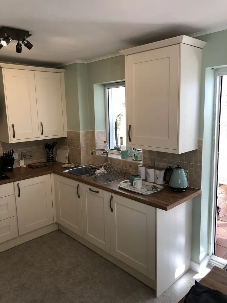 Cream shaker kitchen with oak worktop, square ceramic tile splashback, and mint green walls, fully completed in Southville